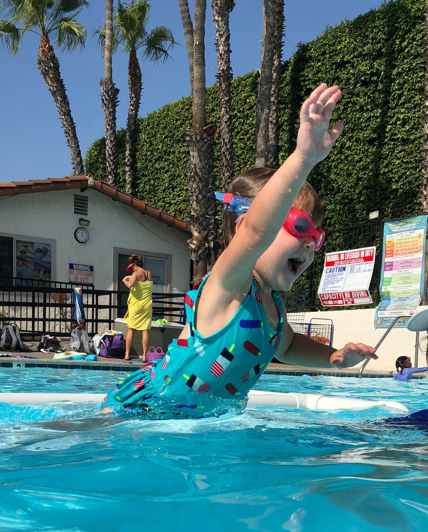 Young girl with goggles jumping into the pool during swim lessons at Nova Swim School