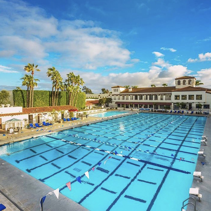 Los Caballeros Racquet and Sports Club outdoor swimming pool surrounded by palm trees in Fountain Valley