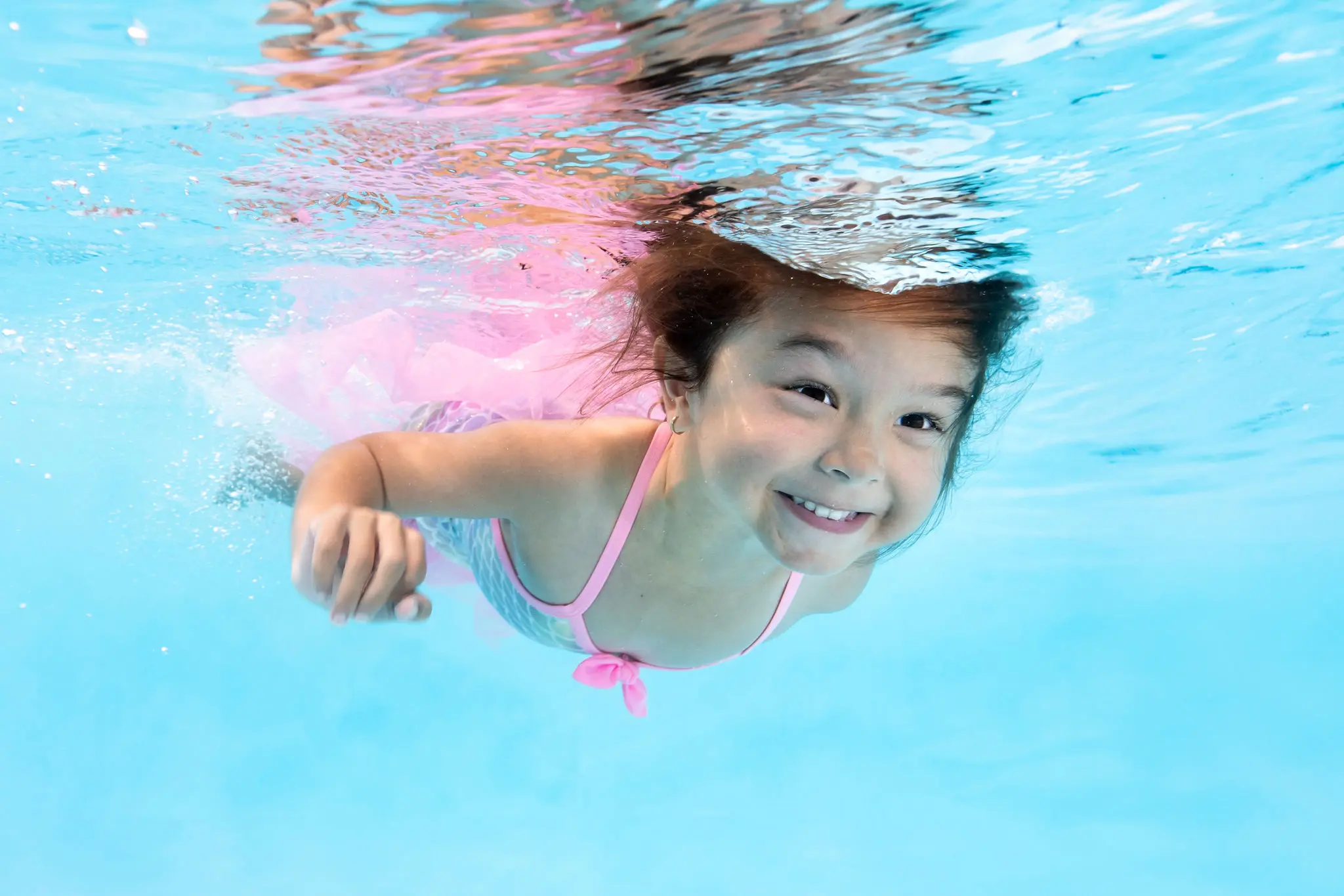 Fahey-21 Young girl smiling while swimming underwater during a swim lesson